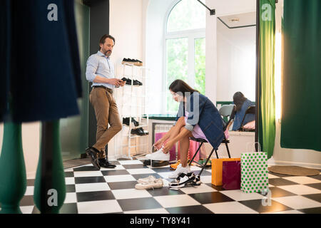 Femme élégante d'essayer de nouvelles chaussures dans le magasin de vêtements Banque D'Images