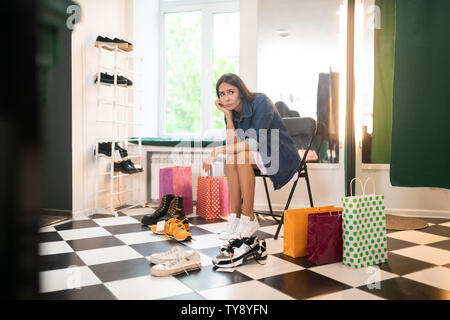 Belle femme sentiment difficile faire des choix dans la boutique de vêtements. Banque D'Images