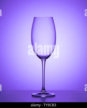 Verre de vin vide sur fond violet. close up. Banque D'Images