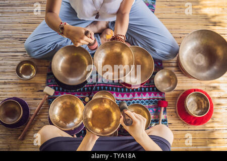 Le Népal en cuivre Bouddha bol chantant au spa beauté. Belle jeune femme faisant la massothérapie singing bowls dans le Spa contre une chute d'eau. Thérapie sonore Banque D'Images