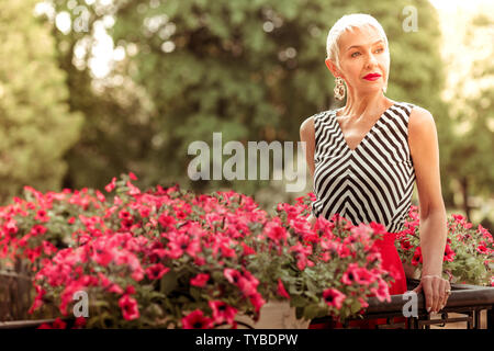 Appel mature woman wearing nice boucles d'debout sur balcon Banque D'Images