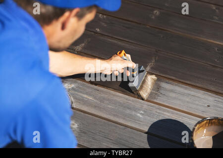 Terrasse en bois peinture homme bandes avec de l'huile de protection du bois Banque D'Images