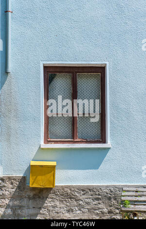 Fenêtre et une boite aux lettres jaune sur un mur bleu sur une maison, avec ombres télévision rappelant le style design Banque D'Images