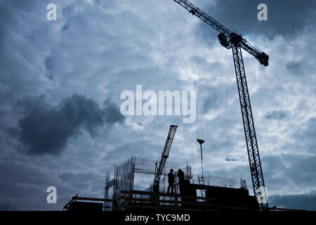 Silhouette de deux travailleurs sur le haut d'un immeuble en construction Banque D'Images