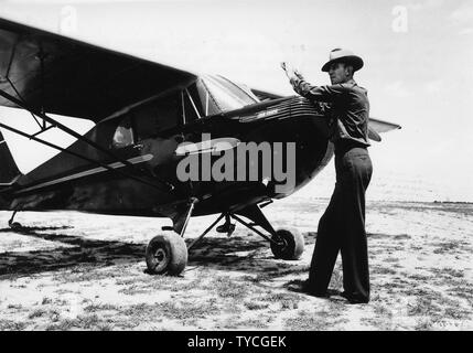 Photo de Laurent Battey de démarrer le moteur de l'avion Piper Cub coupé ; Portée et contenu : sous-titre original : M. Lawrence Battey, de Salem Ranger District, démarrer le moteur de l'avion Piper Cub Coupe utilisée sur la Clark NF pour la détection et la patrouille des feux de forêts. Banque D'Images