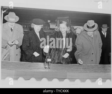 Photo de Margaret Truman laissant tomber une pièce de monnaie dans une bouteille marquée... dans le cadre d'une apparition publique en faveur de la March of Dimes, tandis que Bess Truman et deux hommes non identifiés. Banque D'Images