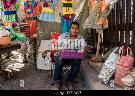 Juan tisse un sac à main à l'ombre à côté de la frontière qui sépare les États-Unis et le Mexique à Mexicali, le 4 avril 2019. Juan a travaillé près de la clôture frontalière pendant 10 ans Vente de vêtements de l'Oaxaca, au Mexique. Photo par Ariana/Drehsler Drehsler UPI Photo par Ariana/UPI Banque D'Images