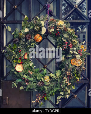 Décoration de Noël à l'extérieur de la porte de la maison. Guirlande de Noël créatif des branches de pins, cônes et d'agrumes. Banque D'Images
