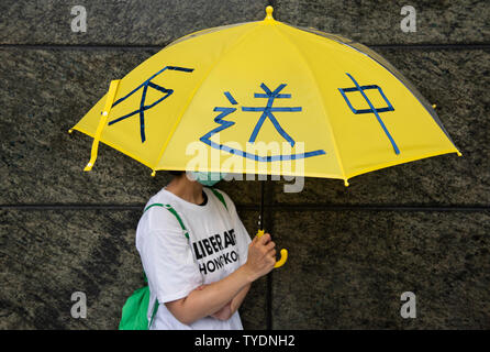 Un manifestant tient un parapluie jaune comme un symbole utilisé à l'égide mouvement, pendant la manifestation des militants.protester contre le projet de loi sur l'extradition s'est rallié aux différentes ambassades et consulats du pays de soulever la question avec le président chinois Xi Jinping, cette semaine, au sommet du G-20 au Japon. Banque D'Images