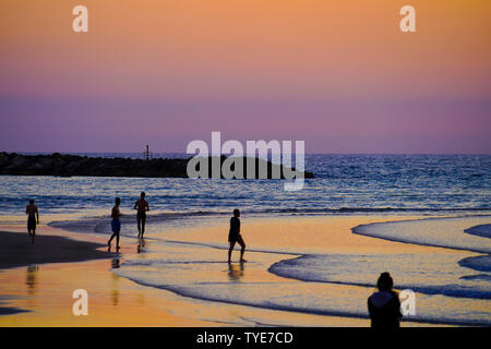 Silhouette de personnes sur la plage au coucher du soleil. Photographié sur la plage de Tel Aviv, Israël en mars Banque D'Images