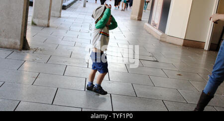 Juin 2019, Cardiff, Pays de Galles. Cute Kids avec leurs parents à l'extérieur St David's Dewi Sant. Fille blonde avec des lunettes, la pram/poussant président Banque D'Images