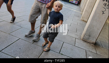 Juin 2019, Cardiff, Pays de Galles. Cute Kids avec leurs parents à l'extérieur St David's Dewi Sant. Fille blonde avec des lunettes, la pram/poussant président Banque D'Images