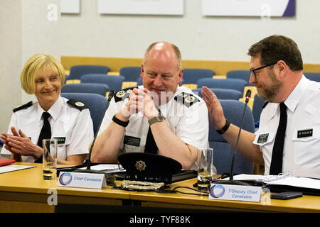 Le chef de police PSNI sortant Sir George Hamilton (centre) est tapoté sur l'arrière par le chef de police adjoint temporaire Stephen Martin (à droite) et applaudis par T/Assistant Chief Constable Barbara Gray au cours de sa dernière réunion de la Commission de police de l'Irlande du Nord à Belfast. Banque D'Images