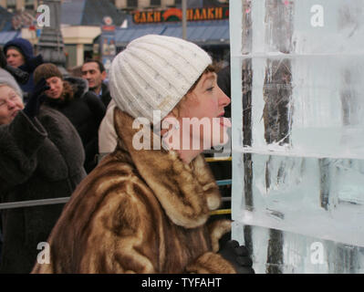 Une femme lèche une partie d'un six mètres de haut sculpture sur glace de Londres Big Ben la tour de l'horloge à la place Pouchkine, à Moscou, le 11 janvier 2006. La sculpture était une partie d'un projet conjoint avec le gouvernement de la ville de Moscou et le bureau du maire de Londres. (Photo d'UPI/Anatoli Zhdanov) Banque D'Images