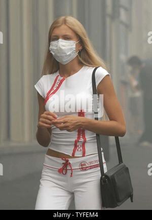 Femme portant un masque de protection de promenades à travers un lourd le smog à Moscou le 6 août 2010. La capitale russe a été couverte d'une épaisse fumée l'enregistrement à l'origine par des températures allant jusqu'à 100 F (38 C) et plusieurs jours de forêt à proximité et feux de tourbe. UPI/Alex Volgin Banque D'Images