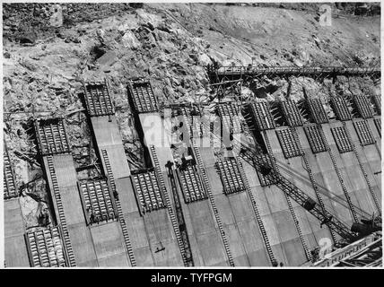 Mise en place de béton en flanc formes de Nevada de déversoir de barrage de Boulder. Le béton est d'être traitées par grue en 2-cube bas-basculer la benne fournie par des agitateurs montés sur camion commandé depuis la centrale à haut niveau. ; Portée et contenu : la photographie de deux volumes d'une série d'albums de photos documentant la construction de barrage Hoover, Boulder City, Nevada. Banque D'Images