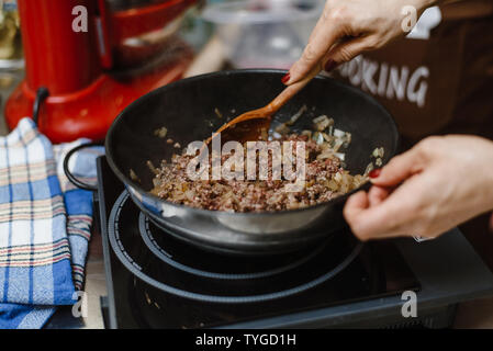 Le chef rôtis l'émincer dans une casserole profonde. Prêt farce avec les oignons dans un bol sur le fond d'épices et les verts. Mélangez la viande frite avec un woode Banque D'Images