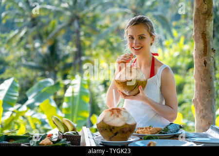 Femme en sirotant un gazebo jungle coconut Banque D'Images