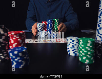 Joueur de poker guy risqué tout-aller en poussant sa pile de jetons de l'avant, les paris à la table de jeux de casino. Gagnant du tournoi de jeu, les gens e Banque D'Images