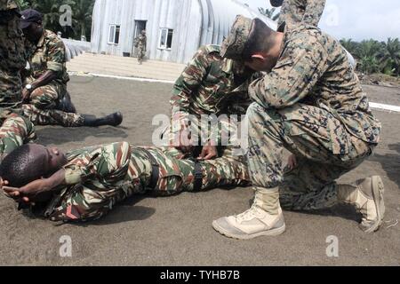 Lance le Cpl. Adrian Arevalo, un carabinier avec des air-sol marin crise Response-Africa Task Force, les entraîneurs un soldat avec le commando naval camerounaises Société l'application d'un garrot à Limbé, Cameroun, 9 novembre 2016. Marines formés ensemble avec l'COPALCO en petite unité tactique, maniement des armes, les premiers soins et les compétences en leadership au cours de leur temps ensemble. Banque D'Images