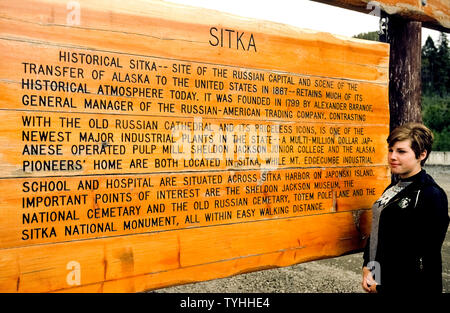 Un visiteur à l'Alaska, USA, lit un signe extérieur en bois qui donne un bref historique de Sitka, qui a été appelé l'Archange nouvelle lorsqu'elle a été la capitale de territoire russe avant que la Russie vend l'Alaska aux États-Unis en 1867. Parmi les sites à voir de Sitka's patrimoine russe est le Saint Michael's 1848 Cathédrale Orthodoxe Russe qui a été détruit par un incendie en 1966 mais reconstruite comme une réplique avec son dôme en forme d'oignon et de l'aiguille du clocher en forme de croix surmontée de Golden. La plupart des icônes de l'ère russe ont été sauvés de l'incendie et sont sur l'affichage à l'intérieur de l'église. Banque D'Images