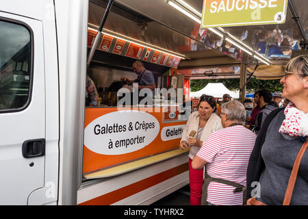 Les gens font la queue pour galette saucisse (saucisse grillée enveloppé dans la crêpe) dans le marché hebdomadaire du jeudi à Dinan, Bretagne, France Banque D'Images