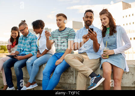 Amis avec les smartphones et les tablet pc en ville Banque D'Images