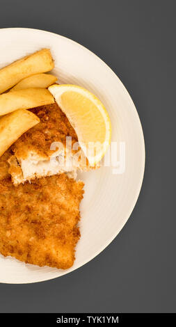 Populaire traditionnel fish and chips sur un arrière-plan gris avec une tranche de citron Banque D'Images