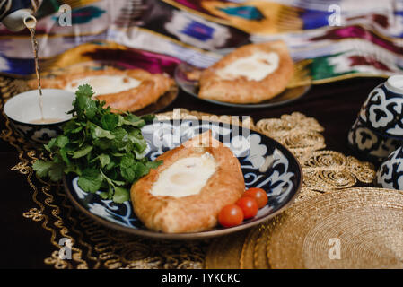 Adjara khachapuri sur la table. l'est dans d'oeufs frais pain chaud sur les plateaux orientaux est dans un restaurant. Banque D'Images