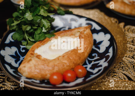 Adjara khachapuri sur la table. l'est dans d'oeufs frais pain chaud sur les plateaux orientaux est dans un restaurant. Banque D'Images