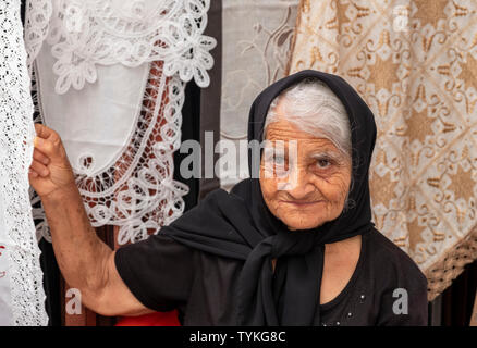 Une dame la vente de dentelle à une échoppe de marché dans la vieille ville de Paphos, Chypre. Banque D'Images