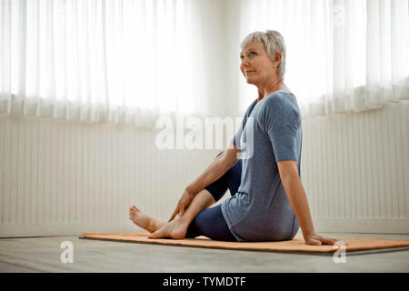 Femme mature pacifiques pratiques étirements de yoga dans son home studio. Banque D'Images