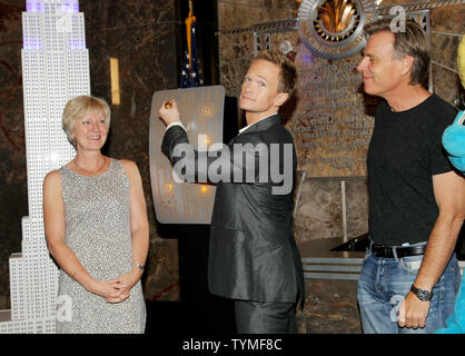 Neil Patrick Harris, centre, jette un interrupteur qui allume un modèle de l'Empire State building bleu que Véronique Culliford, la fille des Schtroumpfs Peyo Culliford, créateur et directeur Raja Gosnell promouvoir 'Les Schtroumpfs' film à l'Empire State Building le 25 juillet 2011 à New York. Le célèbre immeuble phare s'allume en bleu comme les fans sont encouragés à faire un don à l'UNICEF. UPI/Monika Graff. Banque D'Images