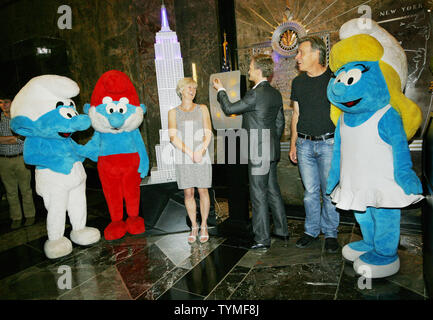 Neil Patrick Harris, centre, jette un interrupteur qui allume un modèle de l'Empire State building bleu que Véronique Culliford, la fille des Schtroumpfs Peyo Culliford, créateur et directeur Raja Gosnell sont rejoint par caractères Smurf pour promouvoir 'Les Schtroumpfs' film à l'Empire State Building le 25 juillet 2011 à New York. Le célèbre immeuble phare s'allume en bleu comme les fans sont encouragés à faire un don à l'UNICEF. UPI/Monika Graff. Banque D'Images