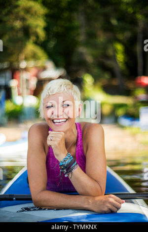 Mid adult woman se prépare pour paddleboarding. Banque D'Images