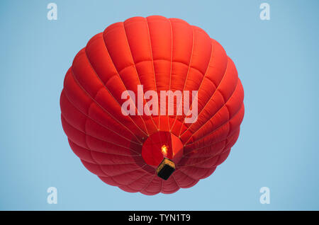 Red hot air balloon dans un ciel bleu clair. Banque D'Images