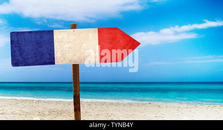 France drapeau sur la table en bois signe sur fond de plage. Il y a plage et l'eau claire de la mer et ciel bleu en arrière-plan. Banque D'Images