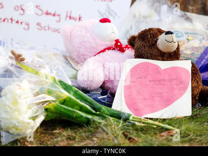 Une note écrite sur un cœur est placé sur un ours et à gauche un mémorial remplis de fleurs, des jouets en peluche et des bougies à l'entrée de l'école élémentaire de Sandy Hook à Newtown, Connecticut à la suite d'un tir de la veille qui a laissé 27 morts dont 18 enfants le 15 décembre 2012. Un homme armé a ouvert le feu à l'intérieur de l'école élémentaire de Sandy Hook tôt vendredi matin où sa mère travaillait. Le suspect de 20 ans, Adam Lanza, qui aurait été tué lui-même après la fusillade à l'intérieur de l'école. UPI/John Angelillo Banque D'Images