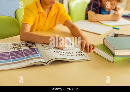 L'étude de l'anglais. Vue de dessus d'un livre en anglais, couché sur le bureau devant un beau jeune garçon Banque D'Images