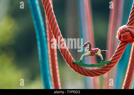 Cheval à bascule en bois anciens lors d'une aire de jeux avec des balançoires corde colorée Banque D'Images