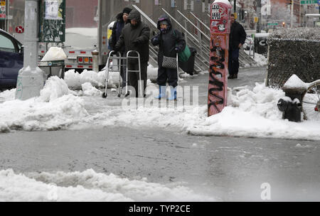 Deux personnes âgées avec des promeneurs, s'arrêter à un passage à niveau et d'oeil à un déluge de glace et de neige fondante sur un coin de rue 1e Avenue dans l'East Village à New York City le 5 février 2014. Une tempête de neige et de glace sous-évaluées que dans la région ont ravagé le mercredi matin pour les navetteurs et les piétons. UPI/John Angelillo Banque D'Images