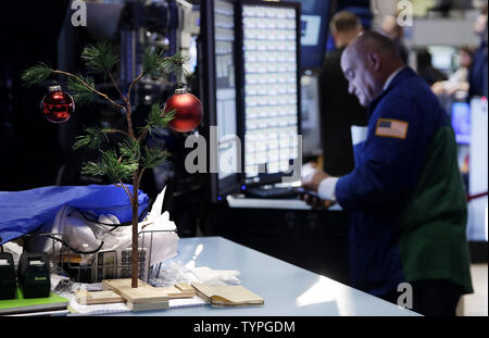 Un petit sapin qui ressemble à celle qui a été rendu célèbre par le dessin animé de Noël spécial 'A Charlie Brown Christmas' se trouve sur un bureau en tant que commerçants travaillent sur le parquet de la Bourse de New York avant la cloche d'ouverture de Wall Street à New York City le 26 novembre 2014. Le nombre d'Américains le dépôt de nouvelles demandes de prestations de chômage, s'est élevé au plus haut niveau depuis septembre. UPI/John Angelillo Banque D'Images