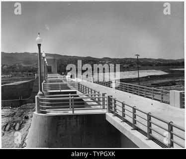 Vue de l'ouest le long du haut de l'évacuateur montrant le service pont et mains courantes. La tour de contrôle de sortie est proche de la gauche, et des travaux en cours sur une partie de l'option Inverser le remblai peut être vu dans la bonne distance. Projet : Los Angeles River Amélioration. Emplacement : Sepulveda Barrage sur Los Angeles River près de Van Nuys, nord-ouest de ville de Los Angeles, Californie. Fonds : fonds réguliers. Travaux poursuivis en vertu du contrat n° W-509-Eng.-966. ; notes générales : - Sepulveda Dam, sur la Los Angeles River dans la vallée de San Fernando. Banque D'Images