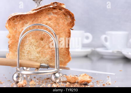 Argenterie ancienne toast rack avec des tranches de pain frais et de tasses de café dans l'arrière-plan, pendant le petit déjeuner Banque D'Images