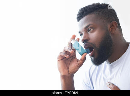 Jeune homme à l'aide d'asthme inhalateur à la maison Banque D'Images