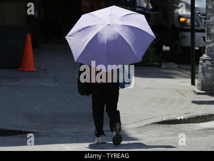 Une femme porte un parapluie pour son bouclier du soleil dans l'East Village de Manhattan à New York City le 25 juillet 2016. Six décès liés à la chaleur ont été signalées comme des températures dangereusement élevées continuent de brûler certaines parties de l'Est des États-Unis, où la chaleur Avis aux médias demeurent en vigueur lundi. Photo de John Angelillo/UPI Banque D'Images