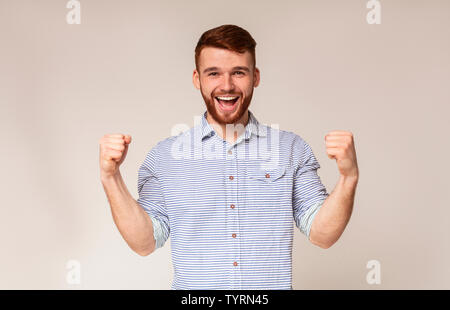 Cheerful guy montrant ses biceps et souriant Banque D'Images