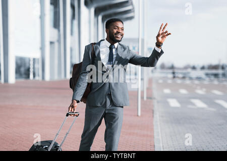 Young Businessman Calling Taxi en arrivant de Voyage Banque D'Images