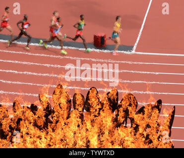 Une chaleur de la Men's 5000M passe devant la flamme olympique au Jeux Olympiques d'été de 2012 à Londres le 8 août 2012 à Londres. UPI/Terry Schmitt Banque D'Images