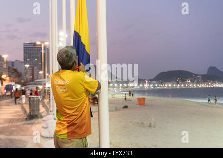Un bénévole aux Jeux Olympiques d'abaisser les drapeaux nationaux le long de la plage de Copacabana au coucher du soleil à Rio de Janeiro, Brésil, 9 août 2016. Les jeux terminer le quatrième jour avec les États-Unis menant les médailles suivie par la Chine et la Russie. Photo de Richard Ellis/UPI.. Banque D'Images